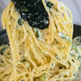 Easy One Pot Creamy Spinach Pasta in Tongs- Closeup Shot.