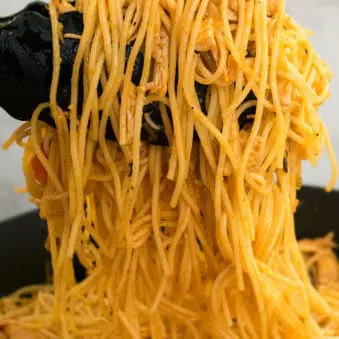 Easy One Pot Cajun Chicken Pasta in Tongs- Closeup Shot.