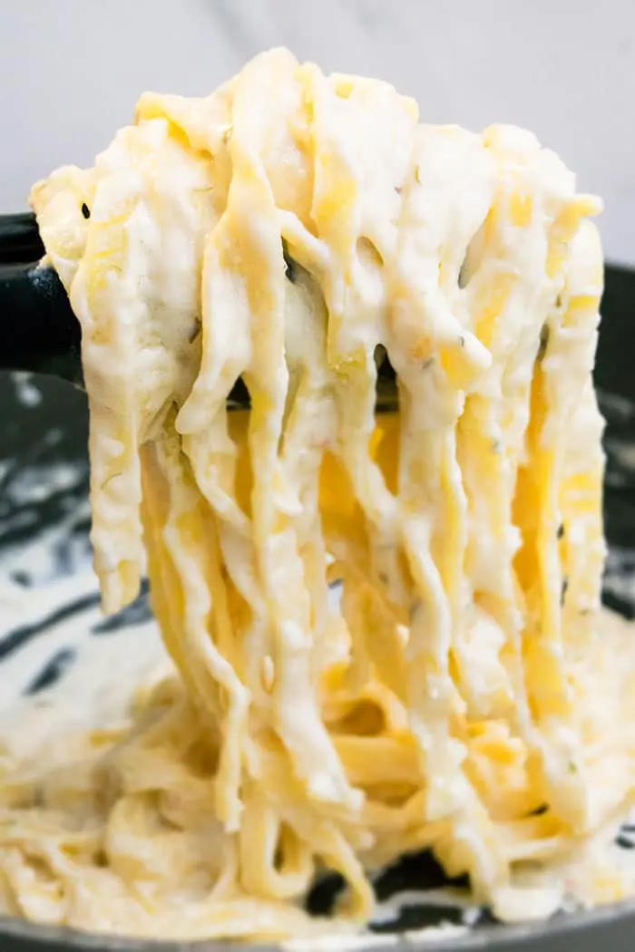 Easy Creamy One Pot Fettuccine Alfredo in Tongs- Closeup Shot.