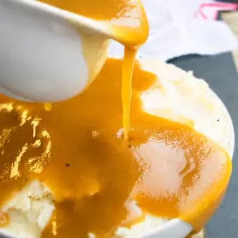 Easy One Pot Brown Gravy Being Poured on Top of Mashed Potatoes.