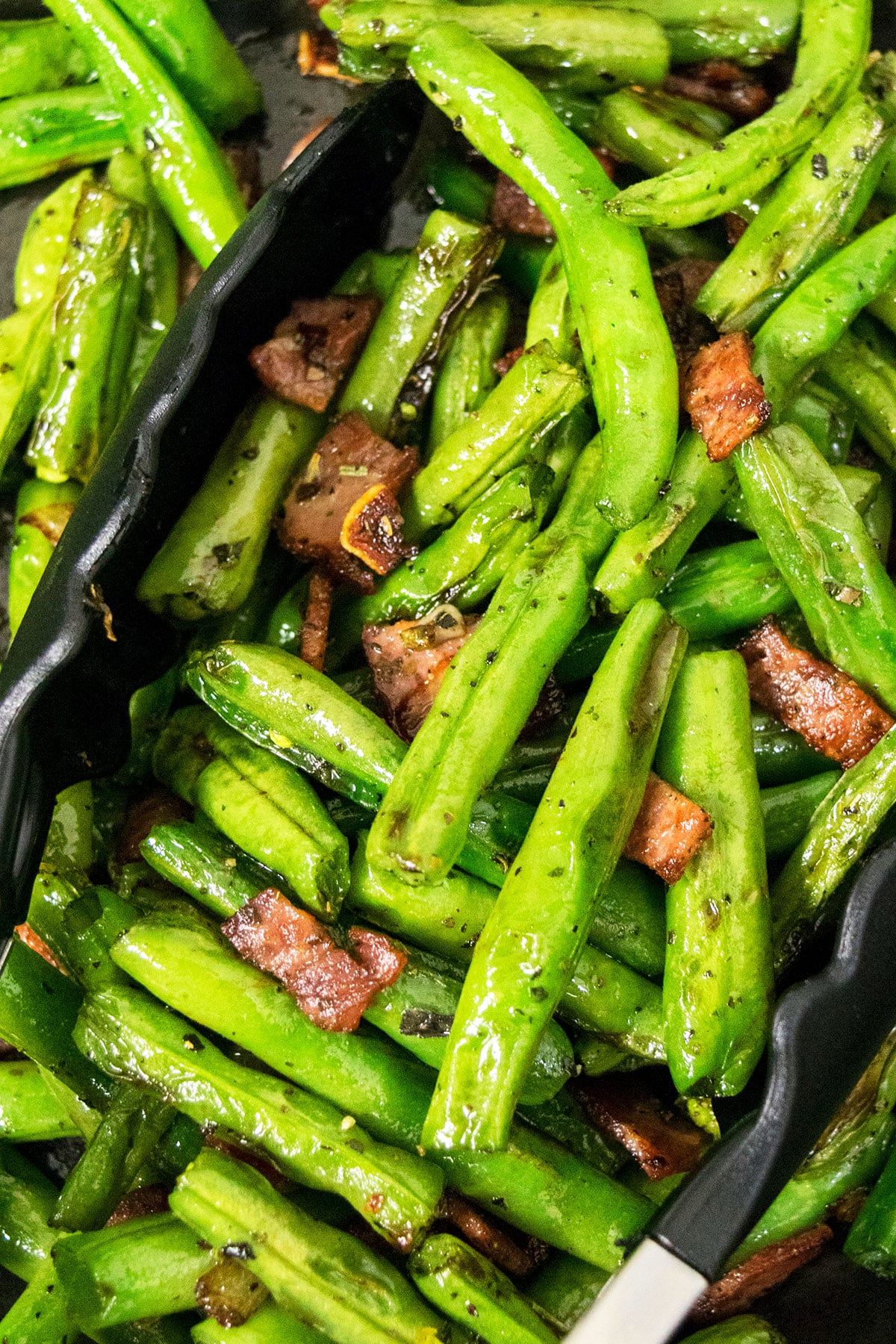 Closeup shot of seasoned green beans side dish with tongs- Closeup shot. 