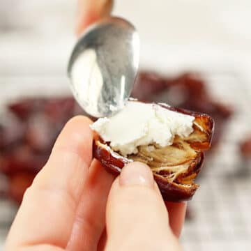 Date being filled with goat cheese using a spoon.