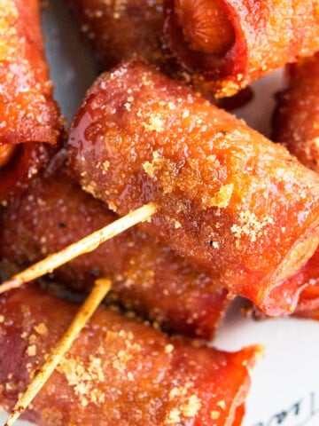 Easy Crispy One Pan Bacon Wrapped Smokies with Brown Sugar in White Dish- Closeup Shot.