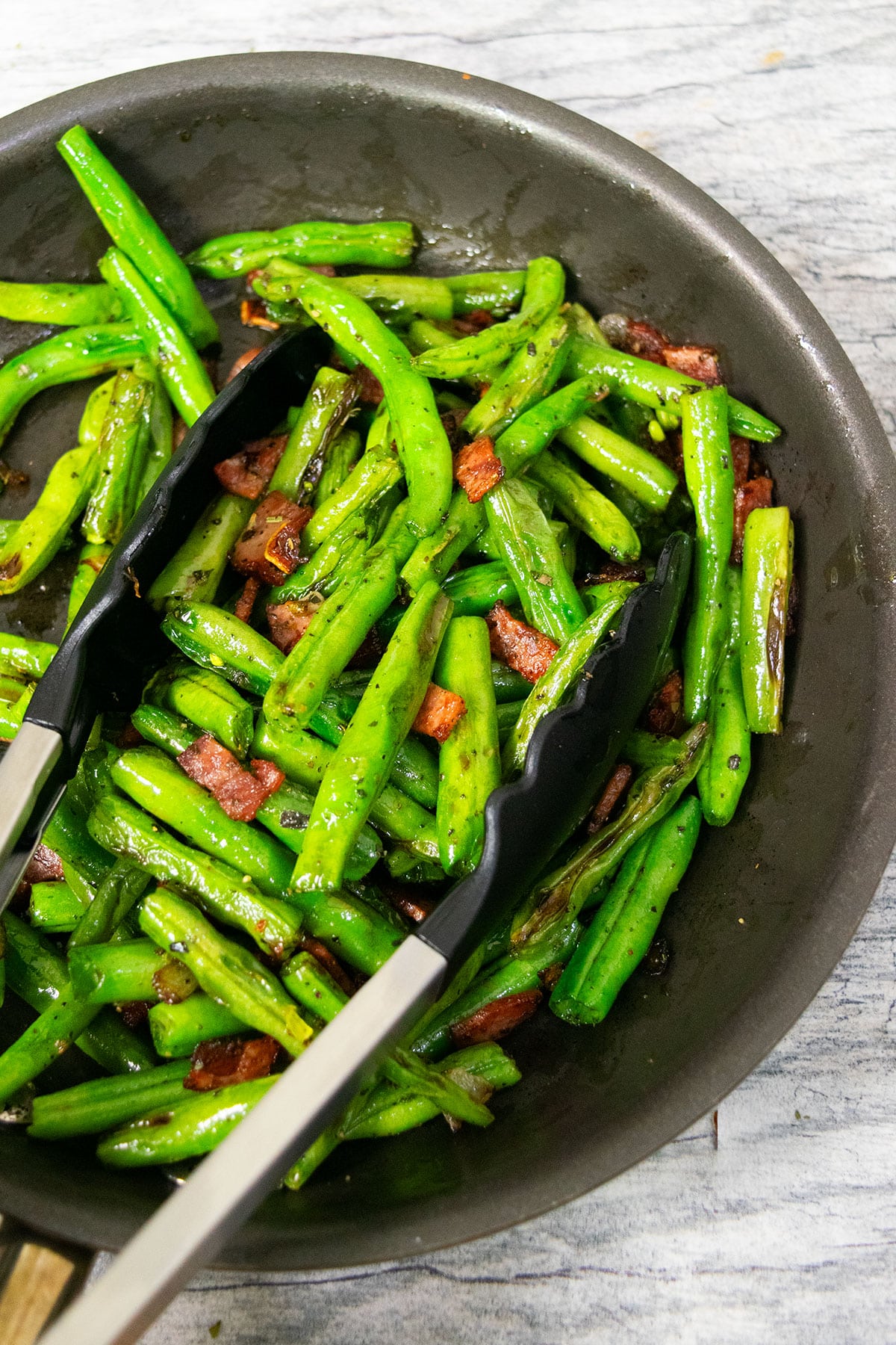 Easy green beans with bacon and onions in black nonstick pot. 