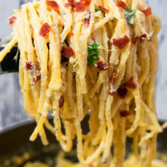 Easy One Pot Chicken Bacon Ranch Pasta Hanging From Tongs With Marble Background.