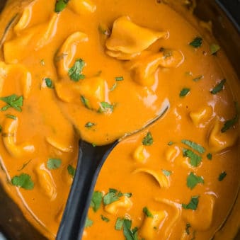 Easy Creamy Slow Cooker Tortellini Soup in Black Crockpot.