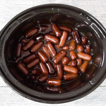 Crockpot without lid with mini sausages covered in sauce. 