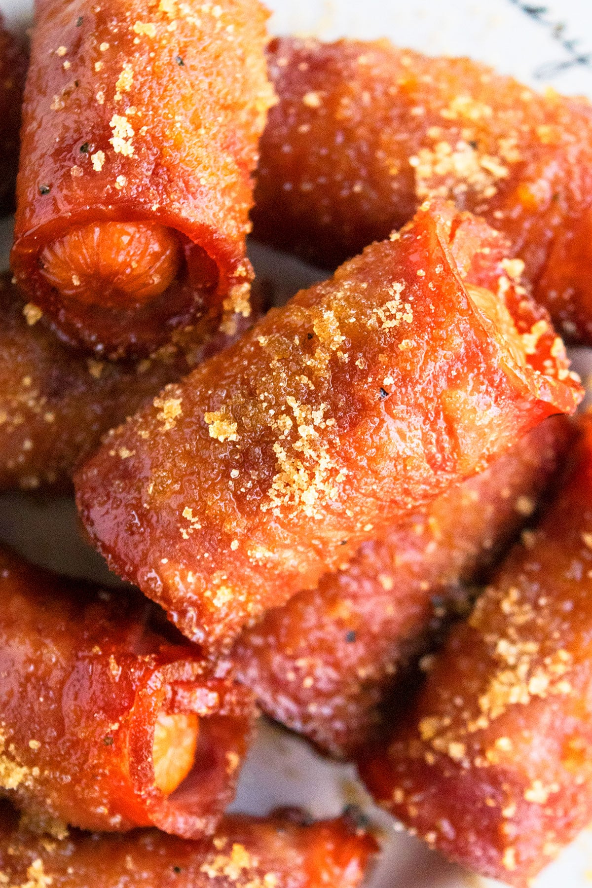 White Dish Full of Baked Mini Sausages Wrapped in Crispy Bacon and Topped With Brown Sugar Appetizer. 