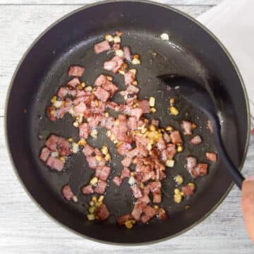 Bacon, onion and garlic being sauted in a nonstick pot. 