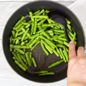 Green beans being sauteed in nonstick pot. 