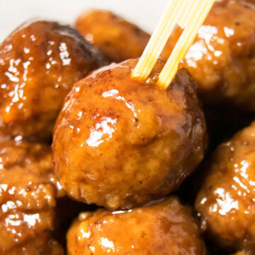 Bamboo toothpick being pushed into the best easy instant pot grape jelly meatballs.