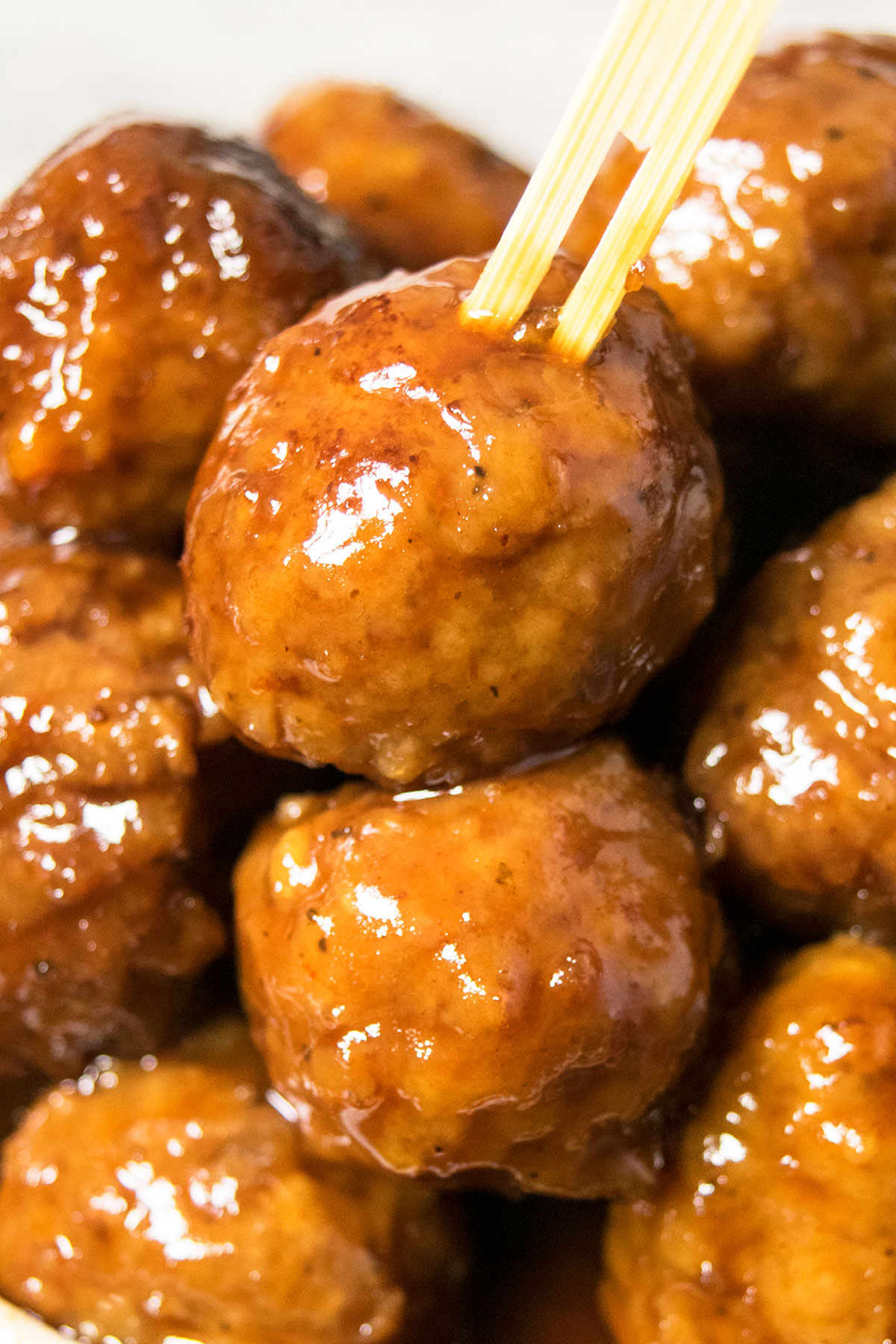 Bamboo toothpick pushed into a sweet and sour meatball- Closeup shot. 