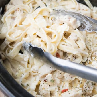 Easy Crockpot Chicken Alfredo With Tongs Inside.