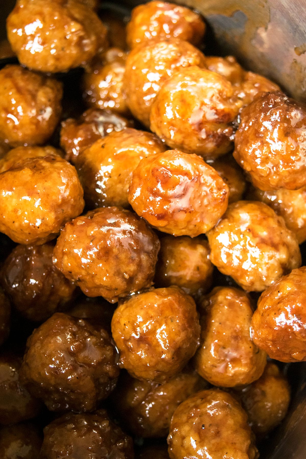 Appetizer meatballs coated in sauce in stainless steel pot- Overhead shot. 