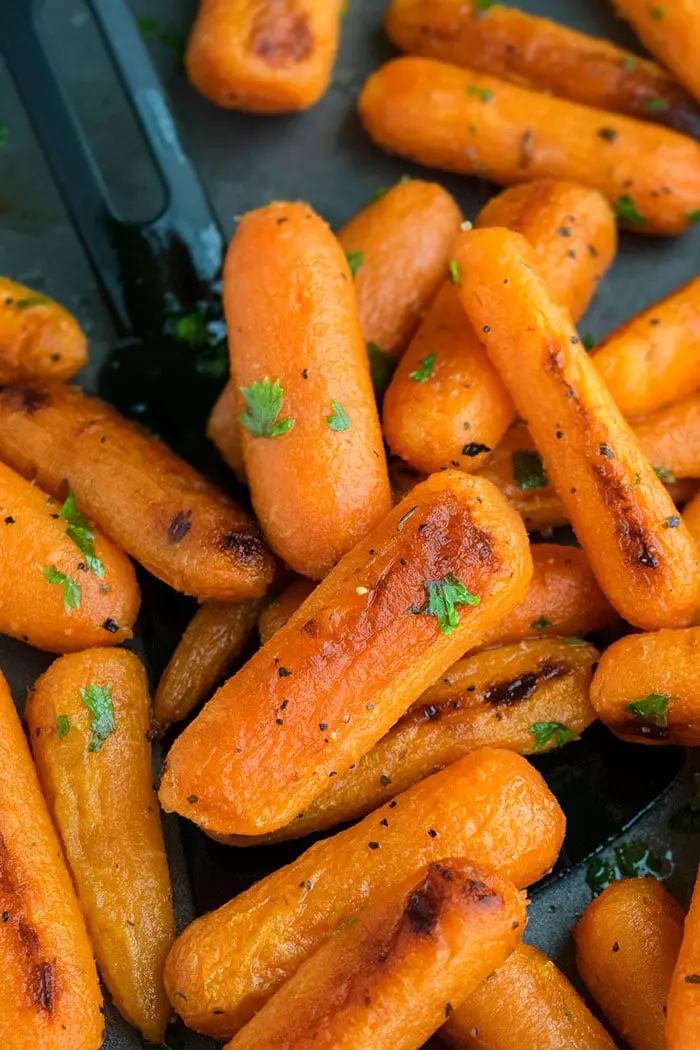 Black Spatula With Baked Baby Carrots on Oven Tray. 