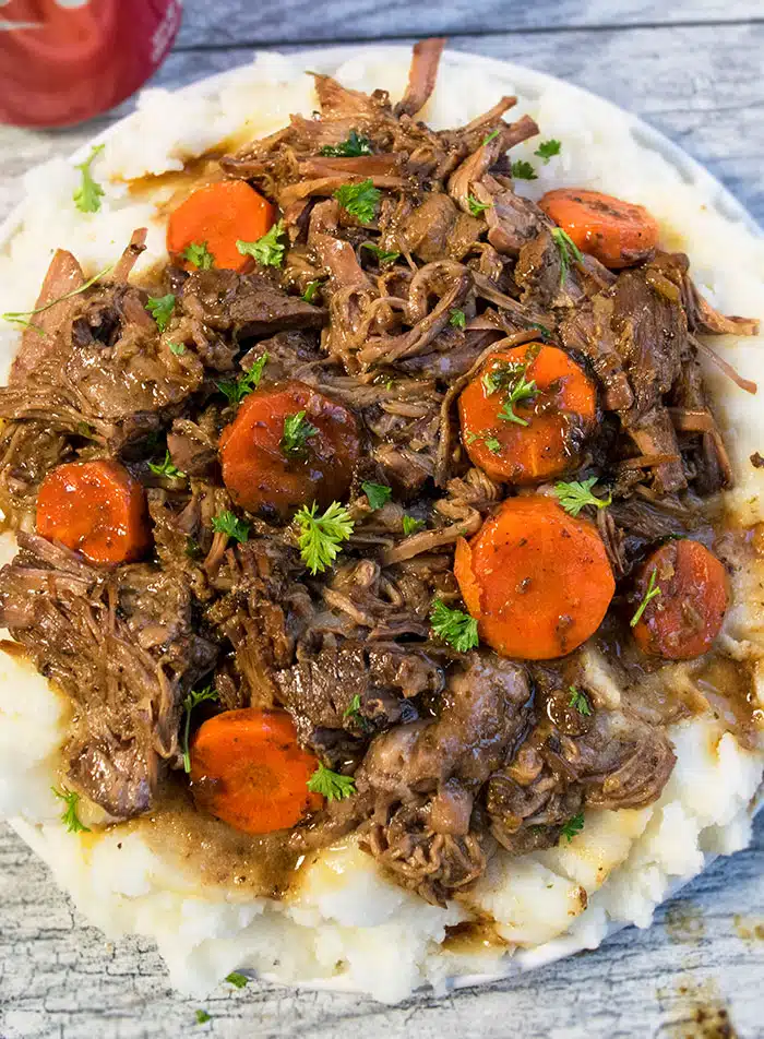 Shredded Meat With Carrots and Gravy on Top of Mashed Potatoes. 