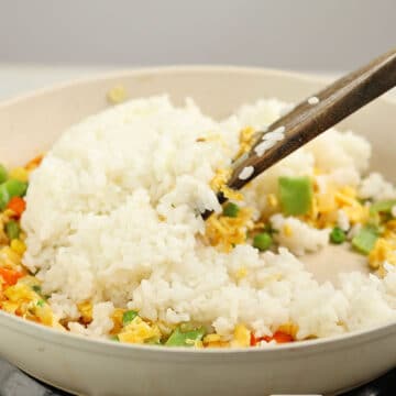 Day old cooked rice bring mixed with the scrambled eggs and veggies.