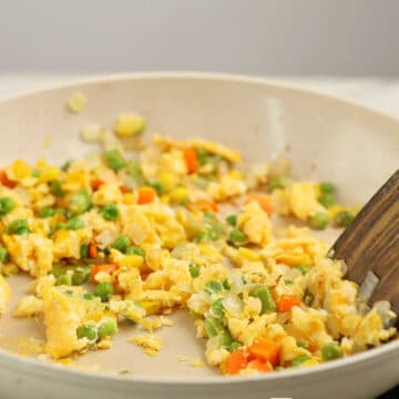 Eggs and veggies being cooked together in nonstick pan.