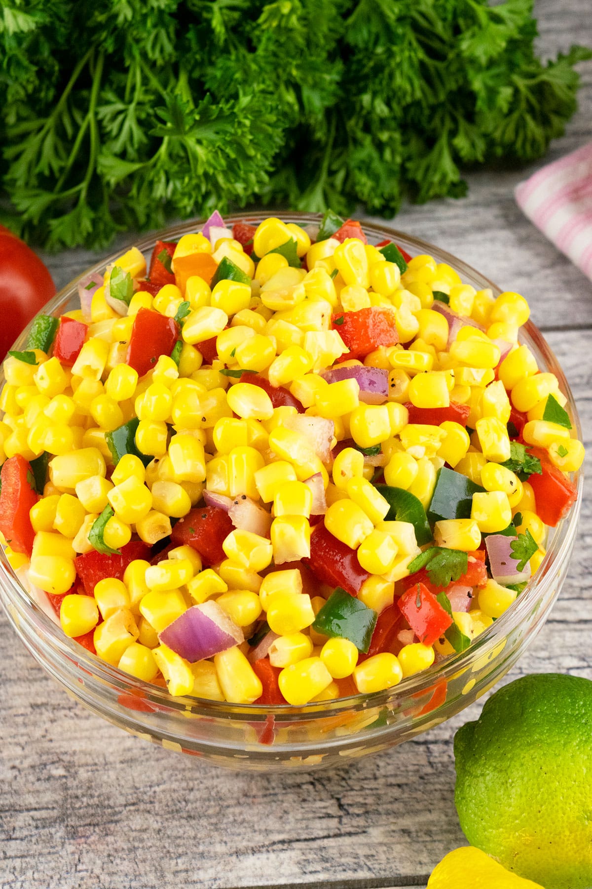Corn with peppers, onions, tomatoes and cilantro in glass bowl. 
