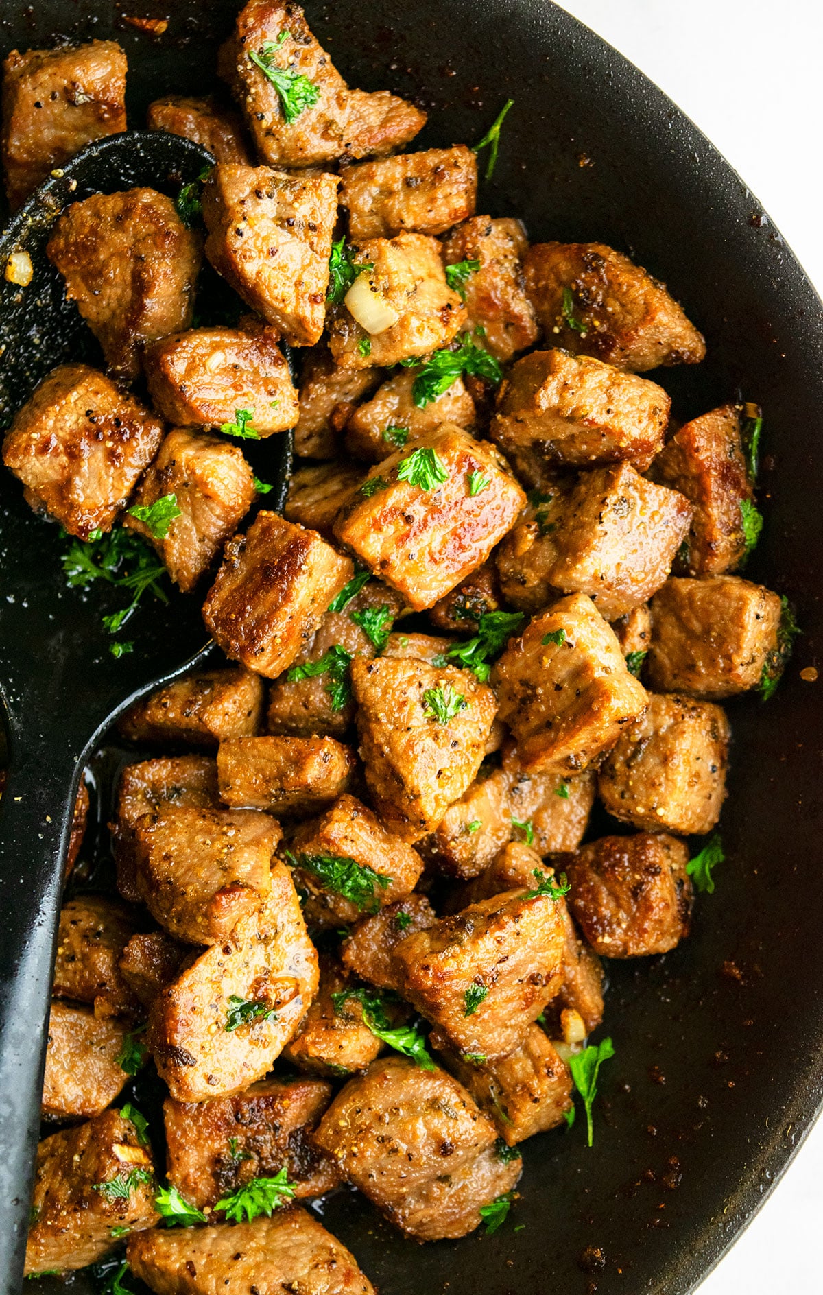 Best easy garlic butter steak bites in nonstick pan with black spoon.