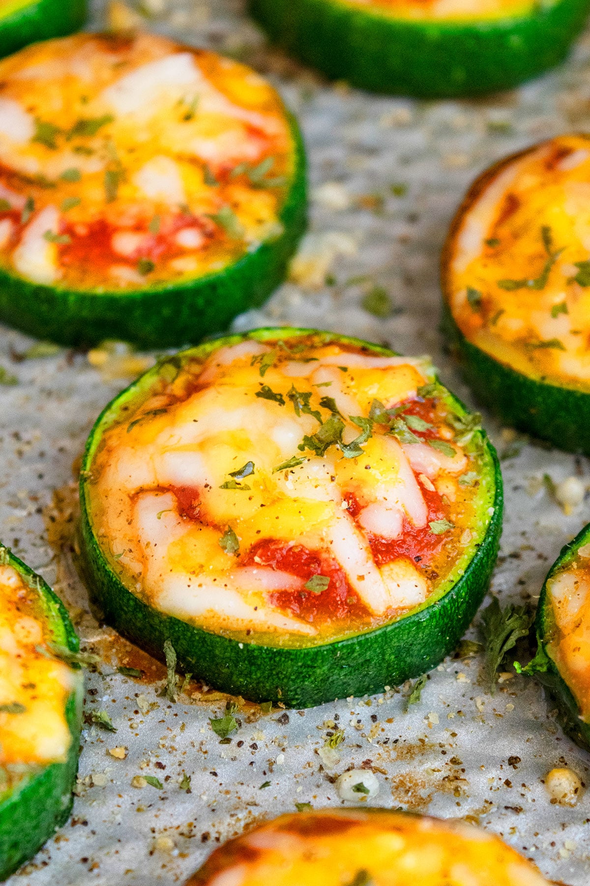 Easy mini zucchini pizza bites with cheese and tomato sauce on baking tray.