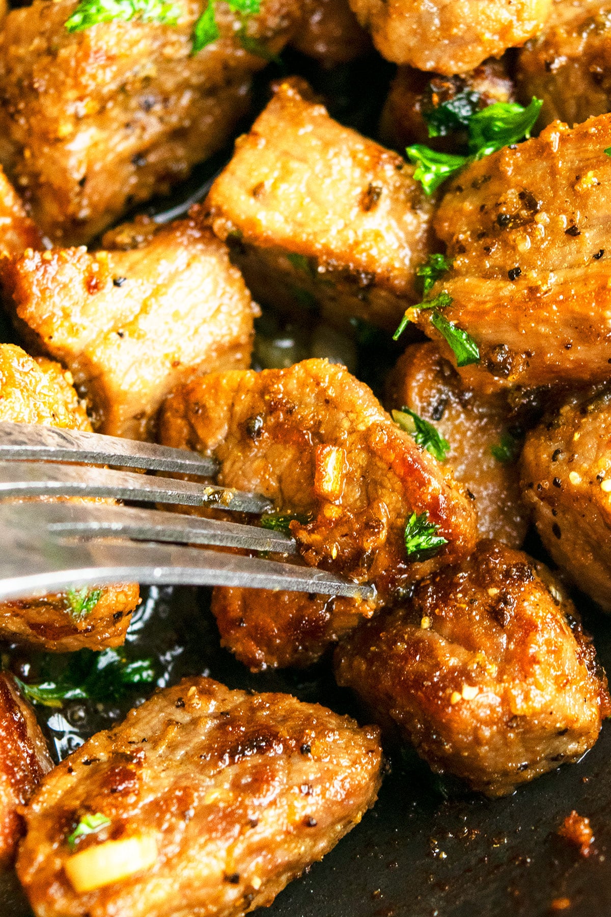 Closeup shot of fork pushing into cooked steak cube.