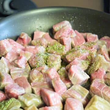 Seasonings added to sauted steak cubes.