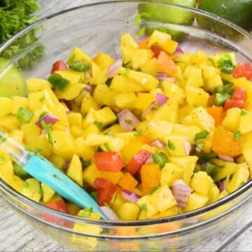 Ingredients being mixed together with spatula in glass bowl. 
