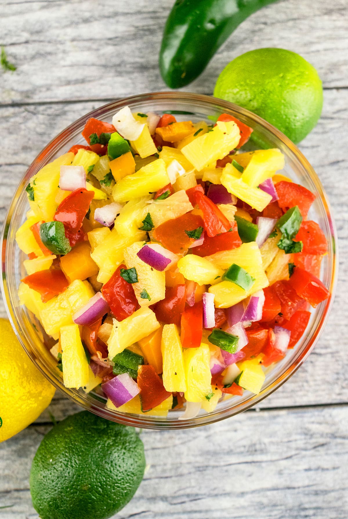 Easy pineapple salsa in glass bowl on rustic gray background- Overhead shot.