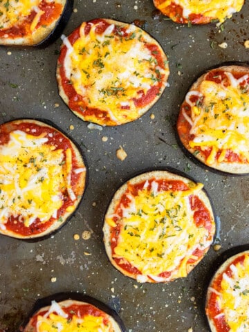 Easy baked eggplant pizza with mozzarella and cheddar cheese on baking tray.