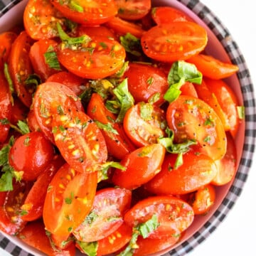 Best easy homemade marinated tomatoes with fresh herbs and spices in black and white bowl.