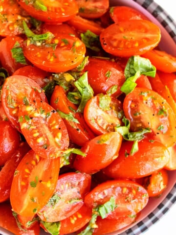 Best easy homemade marinated tomatoes with fresh herbs and spices in black and white bowl.
