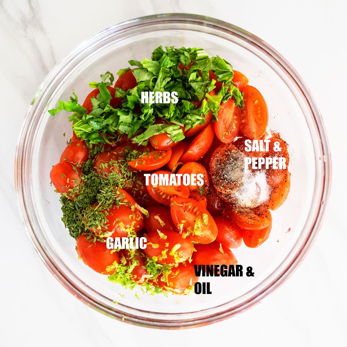 Ingredients in a glass bowl on white marble background ready to be tossed. 