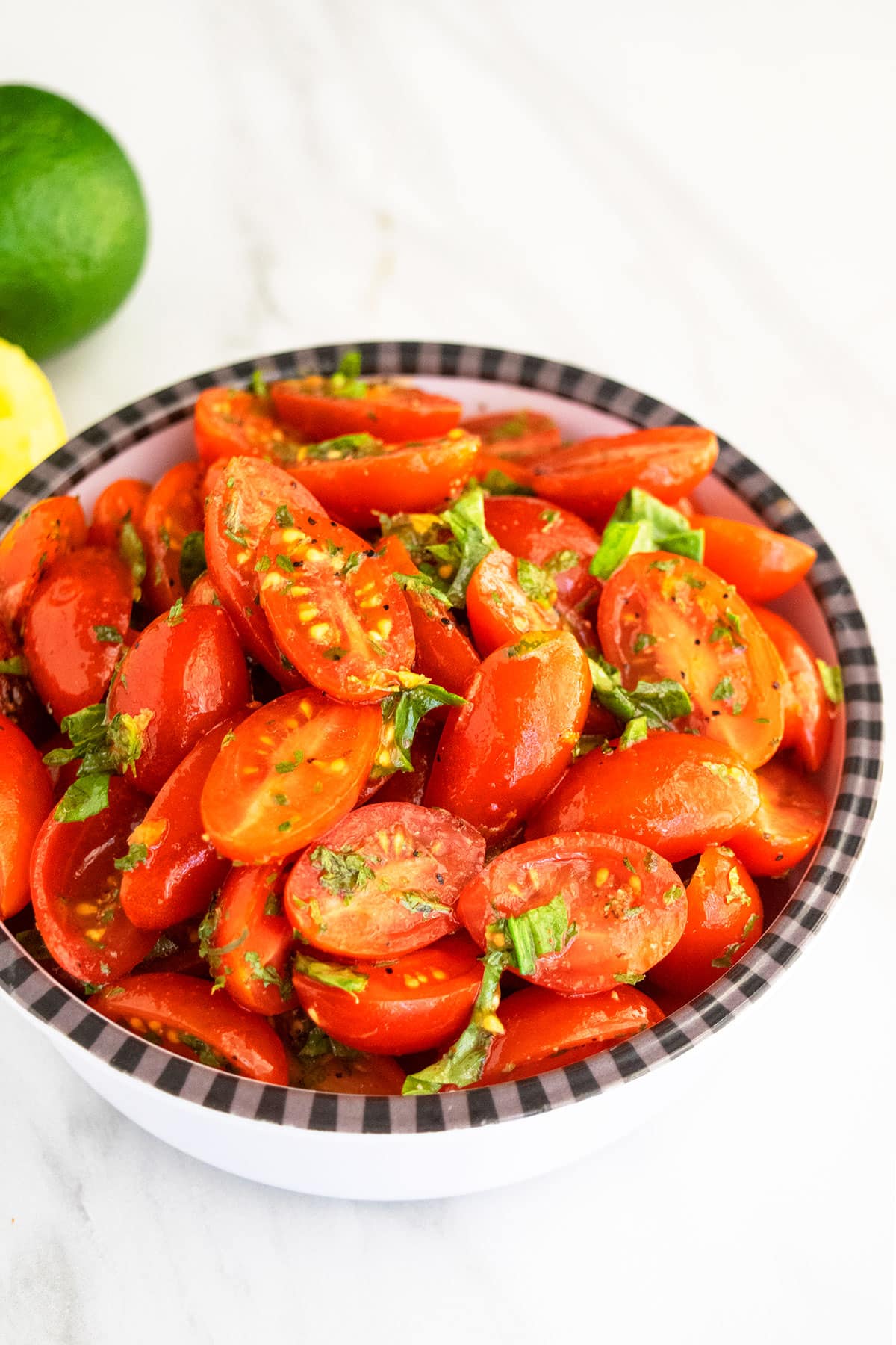 Cherry tomatoes and onions with herbs and spices in black and white bowl. 