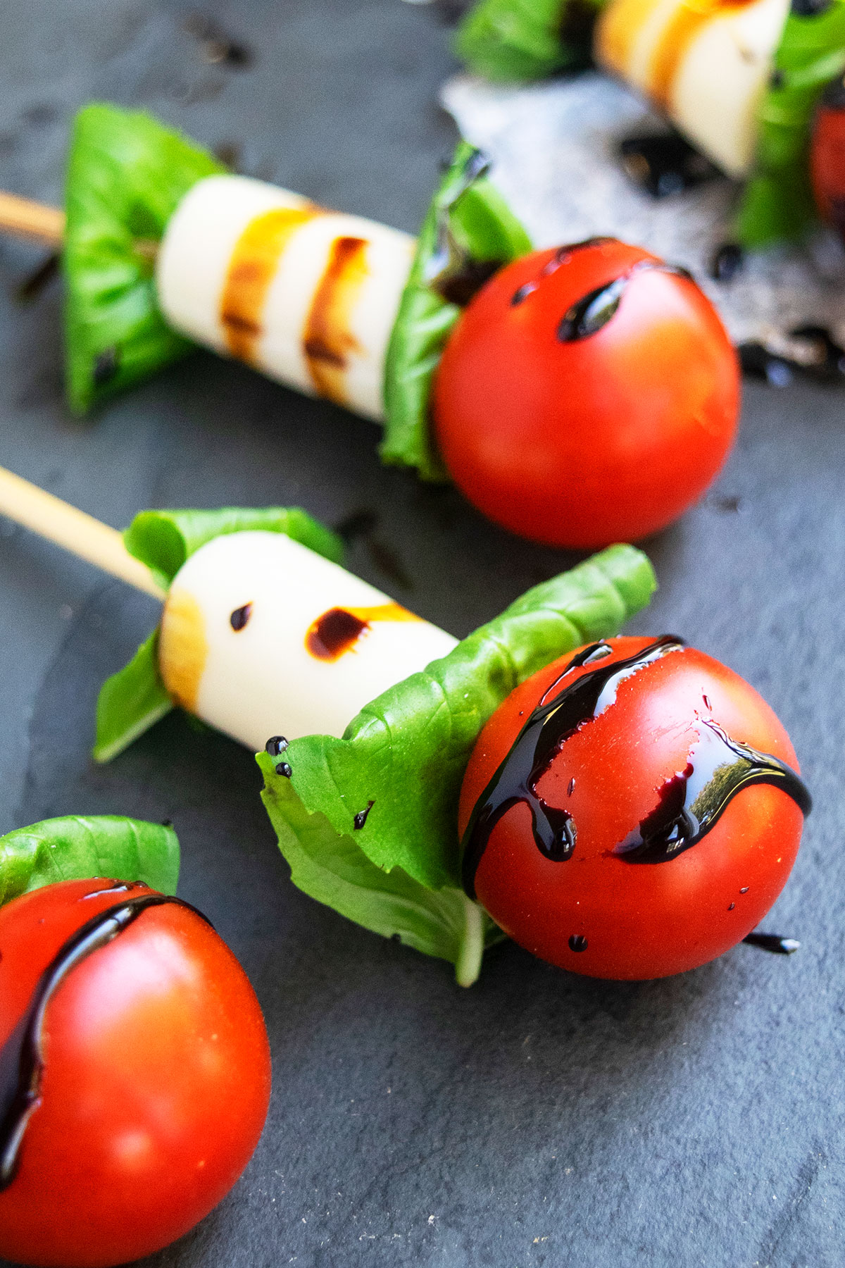 Mini caprese salad kabobs on charcoal gray dish.
