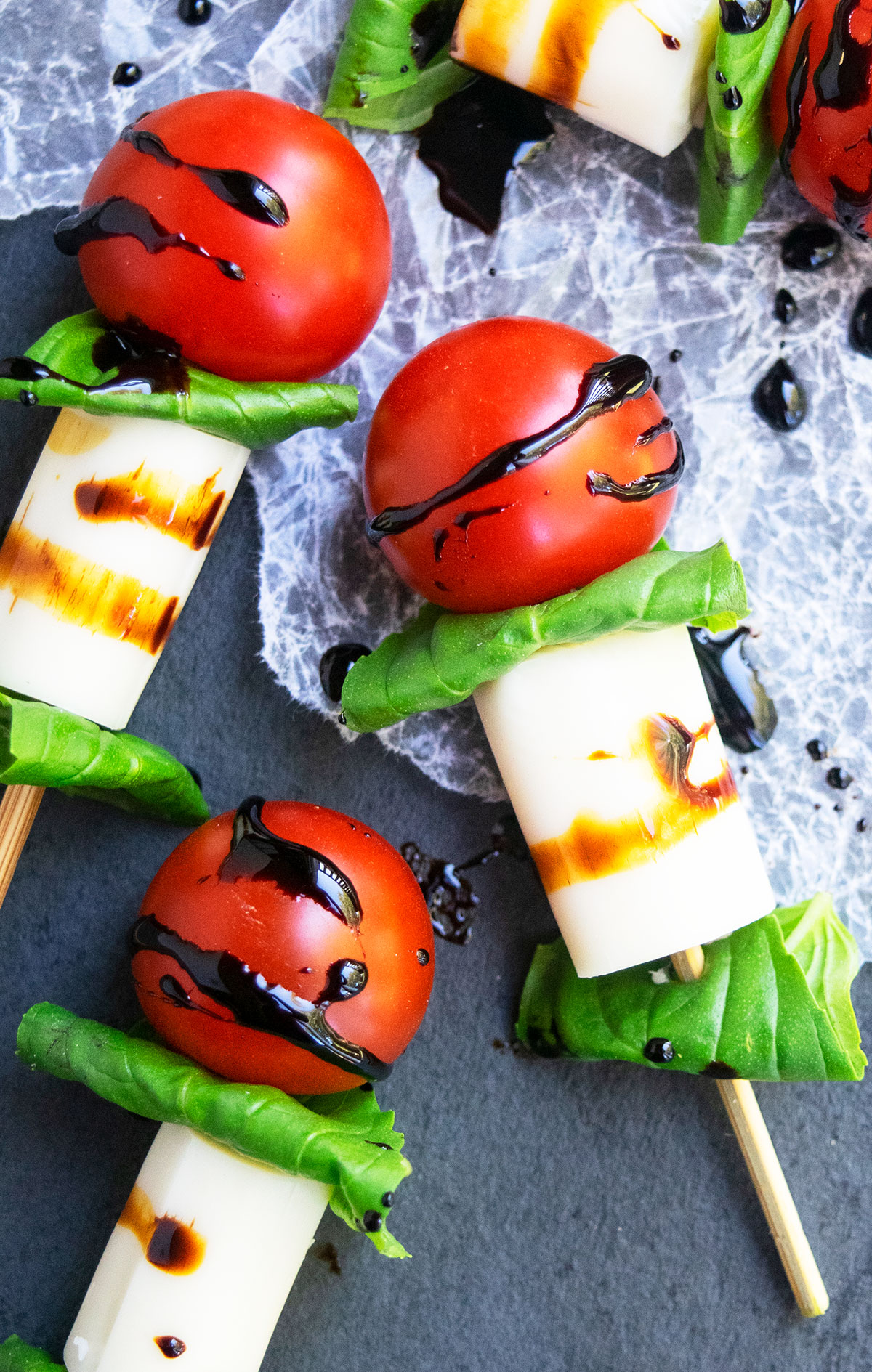 Easy mini caprese skewers with balsamic glaze on charcoal gray dish.