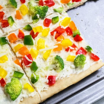 Easy homemade cold crescent roll veggie pizza with ranch on baking tray with one slice removed.