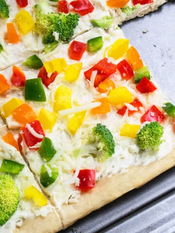 Easy homemade cold crescent roll veggie pizza with ranch on baking tray with one slice removed.