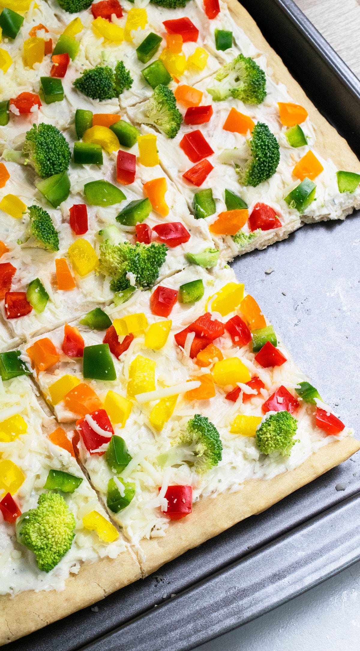 Easy cold crescent roll veggie pizza with ranch on baking tray with one slice removed. 