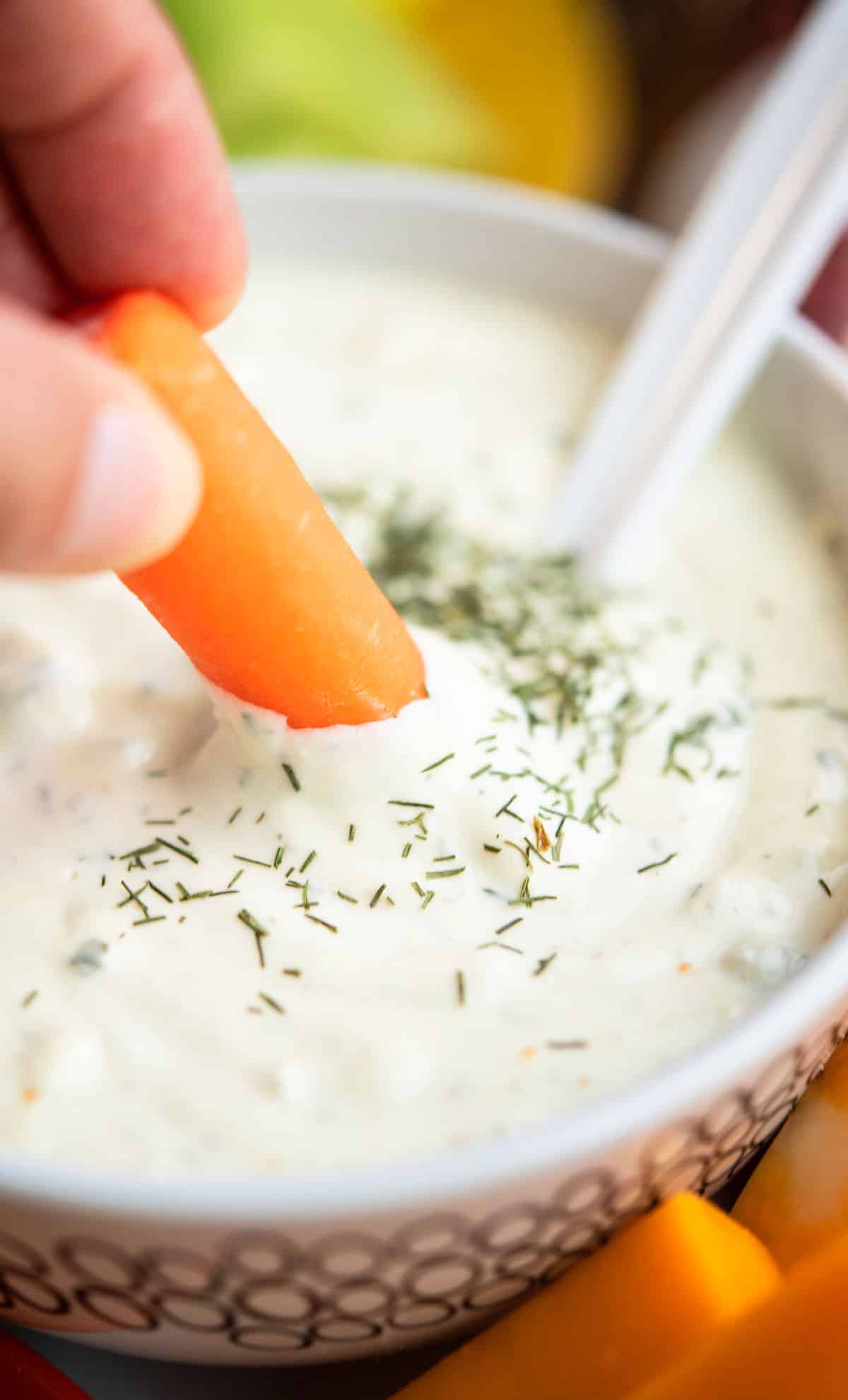 Baby carrot being dipped in homemade dip.