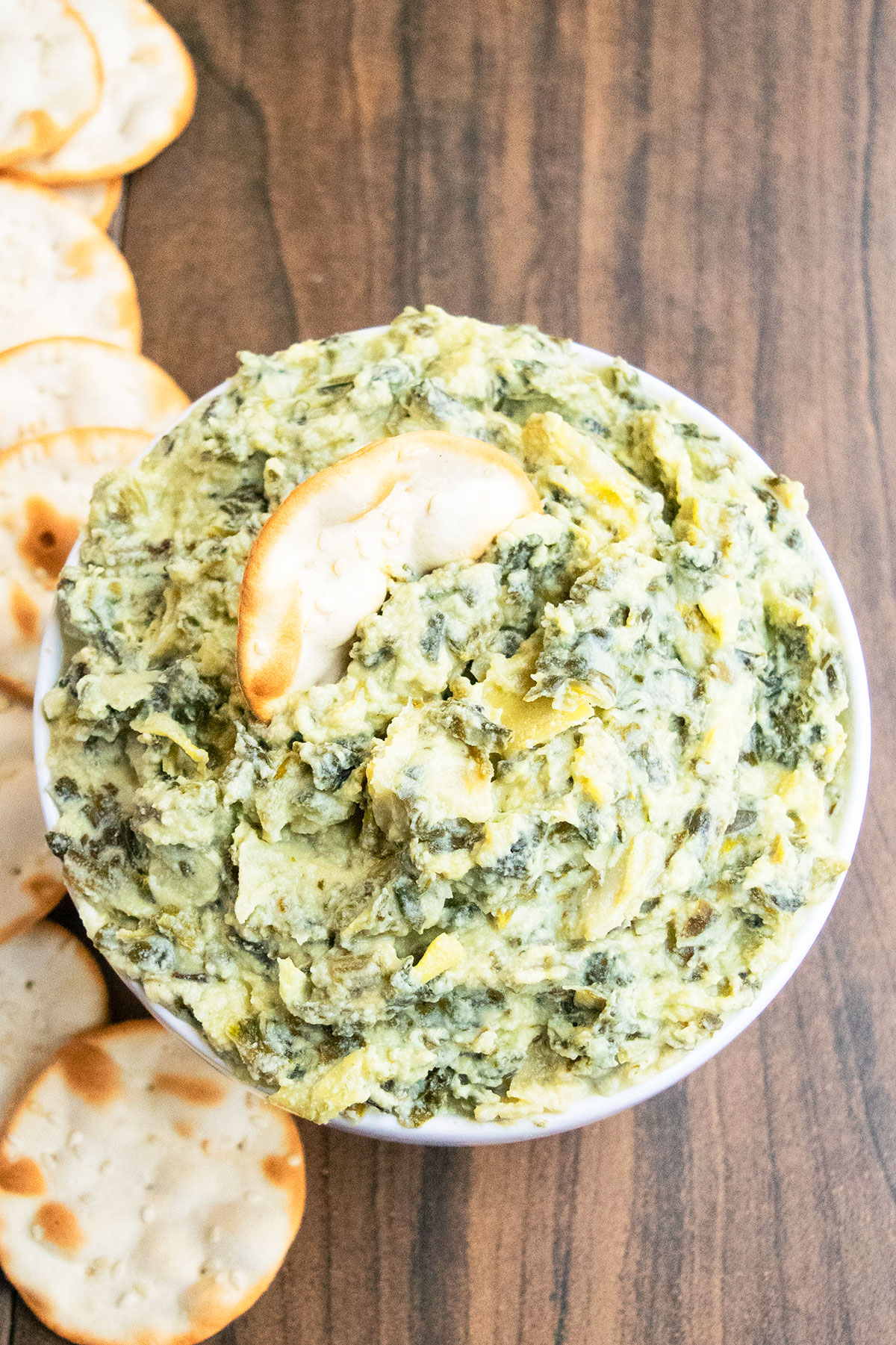 Easy homemade spinach artichoke dip in white bowl with crackers. 