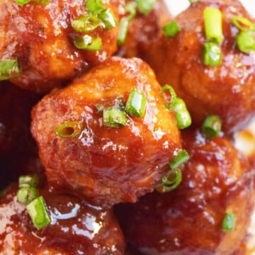 Closeup shot of sweet and spicy coca cola cocktail meatballs or party meatballs in white dish.