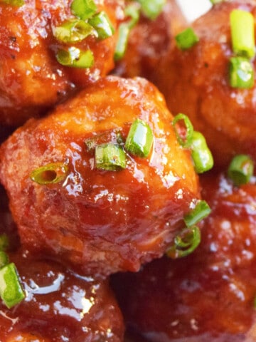 Closeup shot of sweet and spicy coca cola cocktail meatballs or party meatballs in white dish.