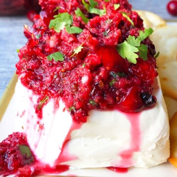 Best easy fresh cranberry salsa spooned over block of cream cheese and garnished with cilantro.