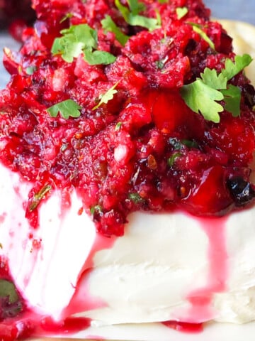 Best easy fresh cranberry salsa spooned over block of cream cheese and garnished with cilantro.