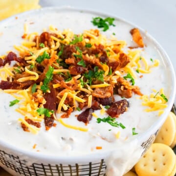 Bowl full of of easy homemade bacon cheddar ranch dip or crack dip on marble background.