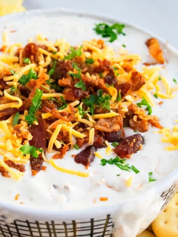 Bowl full of of easy homemade bacon cheddar ranch dip or crack dip on marble background.