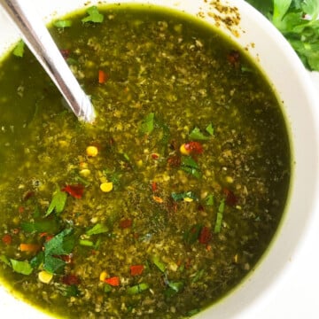 Bowl of easy homemade Argentinian green chimichurri sauce with parsley, cilantro and oregano-Overhead shot.