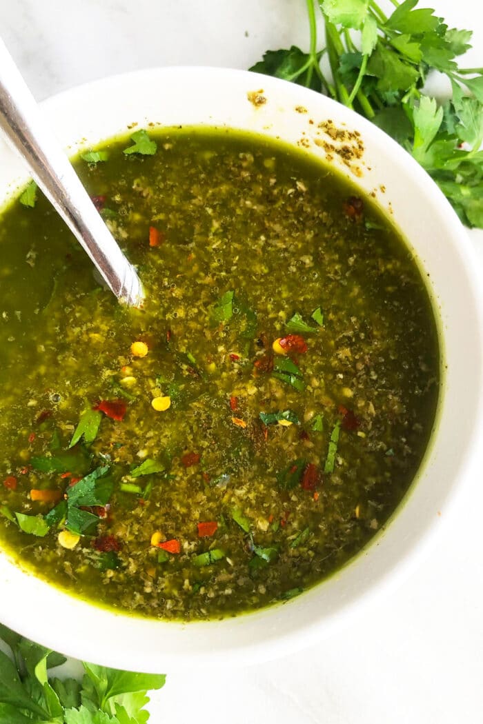 Bowl of easy homemade chimichurri sauce with spoon-Overhead shot. 
