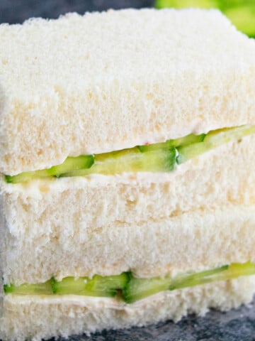 Stack of best easy one pan cucumber sandwiches (English tea sandwiches or finger sandwiches) on gray background.